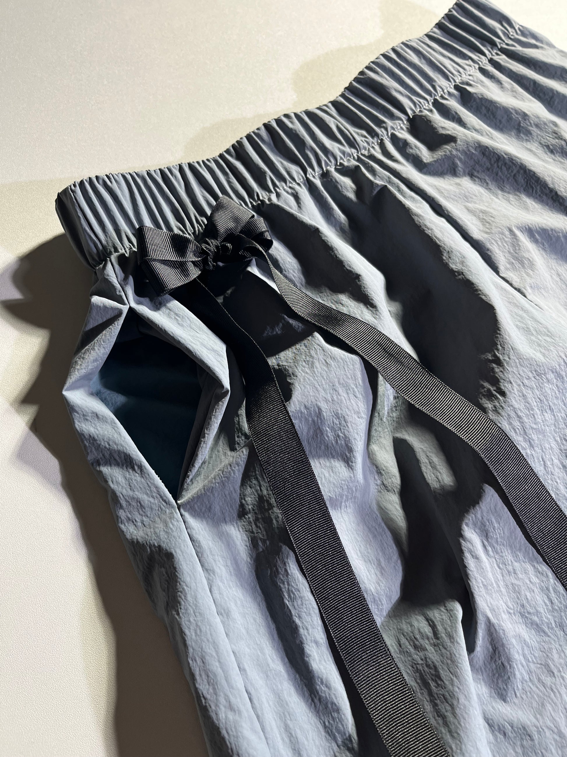BIgger Detail shot of high waisted pants with ribbon detail.