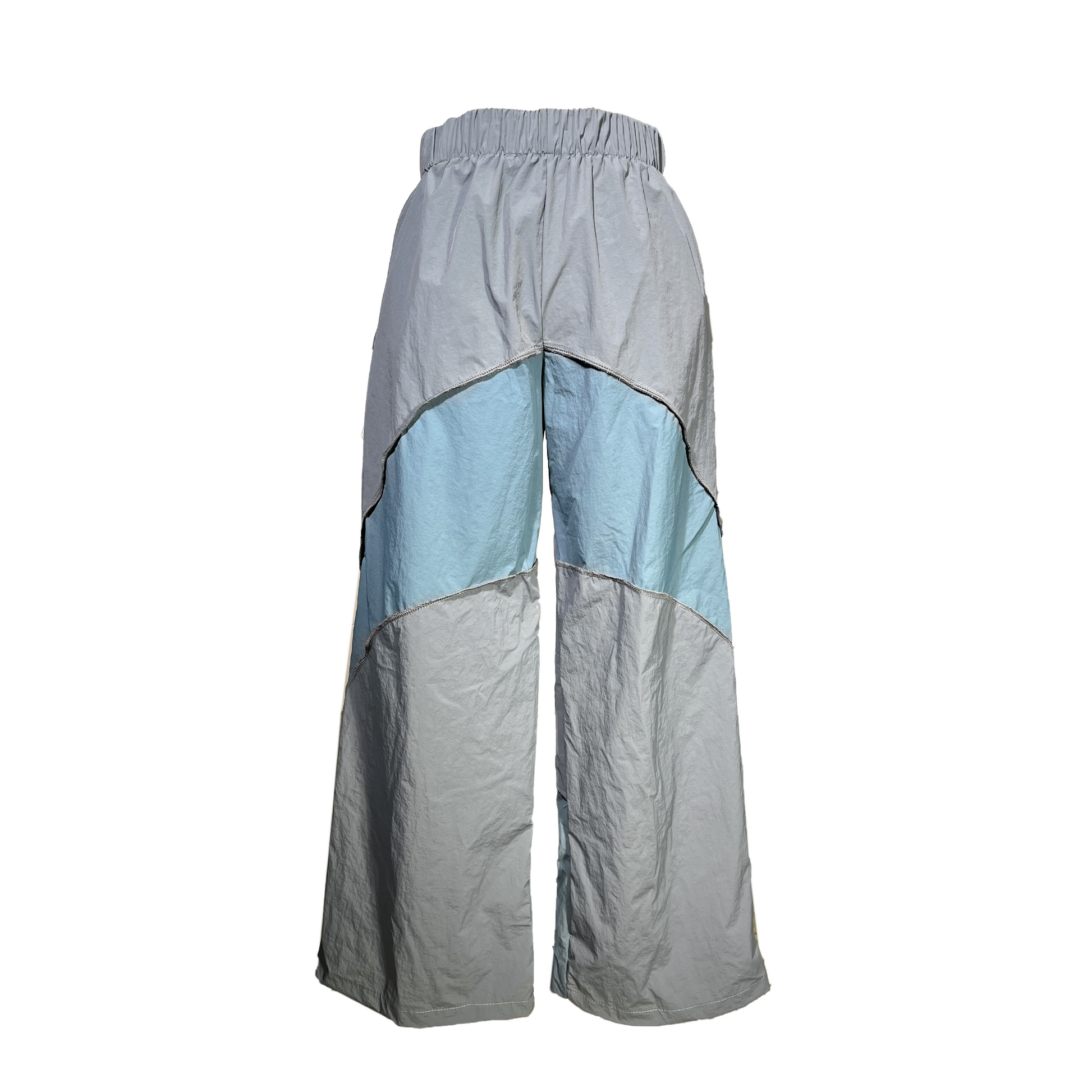 Backside of High waisted loose fitted track pants.
Wide bottom hem for extrem loose fit.
Elastic waistband and side pockets.
Blue panels going from the back to the front.
Inside out stitching detailing.
Bow under the waistband on the right upper hip.
Me dic al Print logo on the left side.